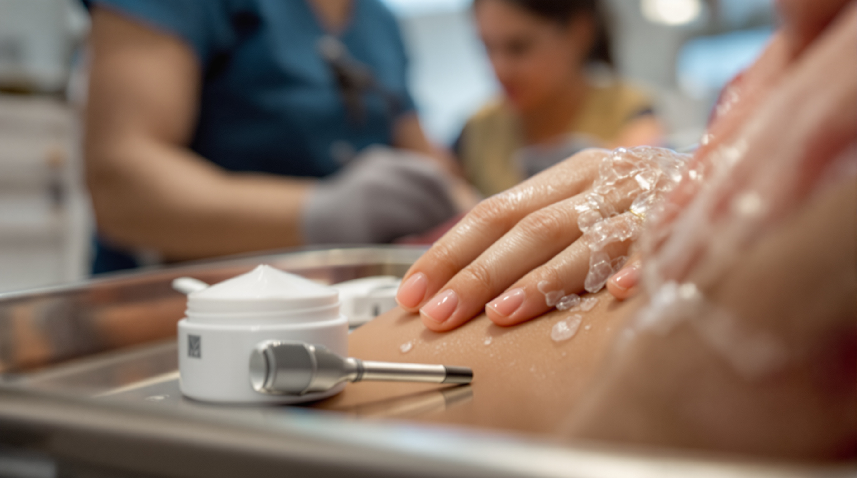 A gloved hand smoothing a thin layer of white numbing cream onto a small patch of skin on a leg in a clean clinic in soft daylight